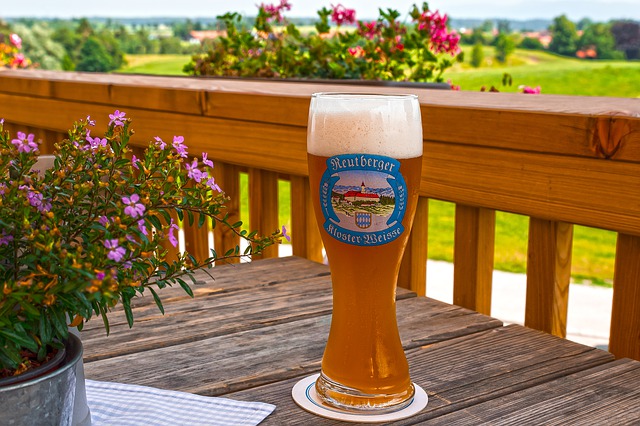 Pivo a kvet na drevenom stole na balkóne pri drevenom zábradlí.jpg